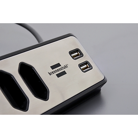 Gros plan d'une multiprise argentée avec deux ports USB. Le logo 'brennenstuhl' est visible.