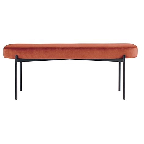 Een gewatteerde bank met roestkleurige fluwelen bekleding en zwarte metalen poten. De poten kruisen elkaar elegant.