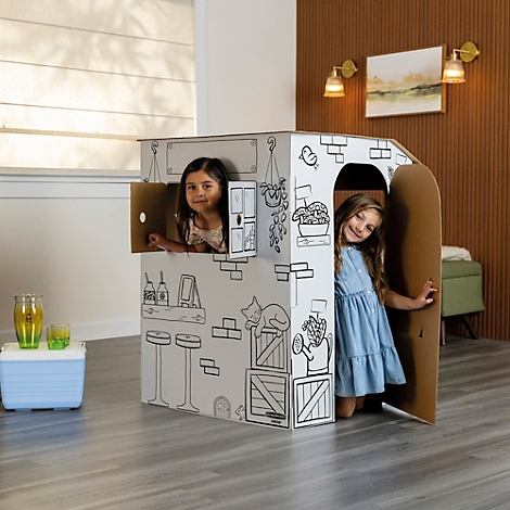 Twee meisjes spelen in een beschilderd kartonnen speelhuis. Het huis is versierd met luiken en versieringen.