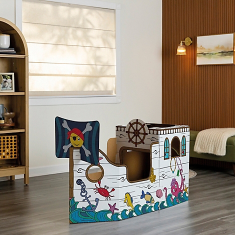 Ein Piratenschiff-Spielhaus aus Pappe mit einem Totenkopf am Mast. Es steht in einem Raum.