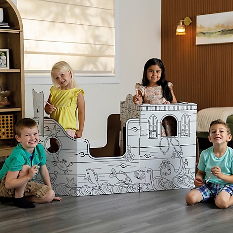 Vier Kinder spielen in einem bemalten Pappschiff. Das Schiff ist von den Kindern bemalt und zeigt Meerestiere.