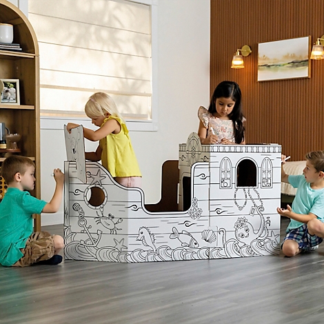 Les enfants colorent un bateau en carton dans le salon. Le navire est décoré d'animaux marins. Les enfants sont heureux.