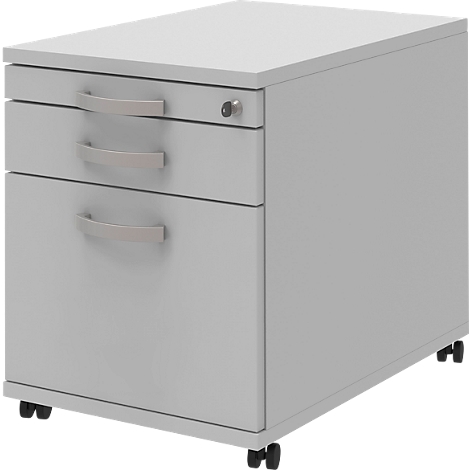 Grey mobile pedestal with three drawers and handles. The top drawer has a keyhole. The cabinet stands on wheels.