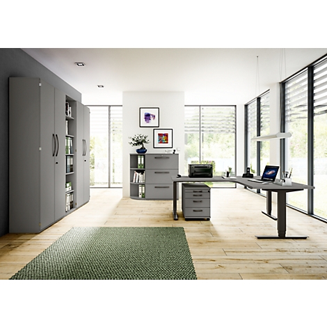 Modern office with gray desk and file cabinets, green rug, windows with blinds, light wooden floors.