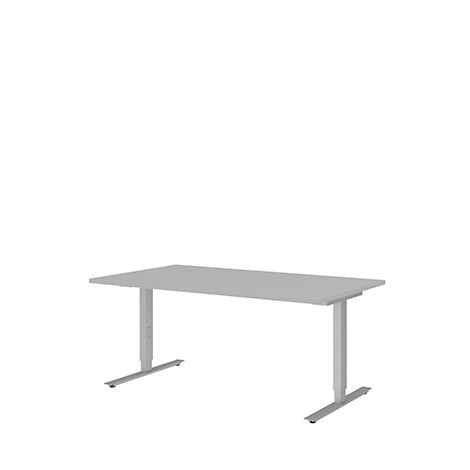 A grey, height-adjustable desk on a white background. The table has a rectangular tabletop and two T-shaped legs.