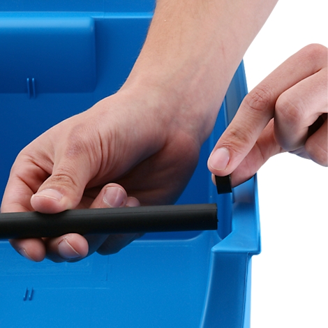 Des mains insèrent une tige noire dans un bac en plastique bleu.