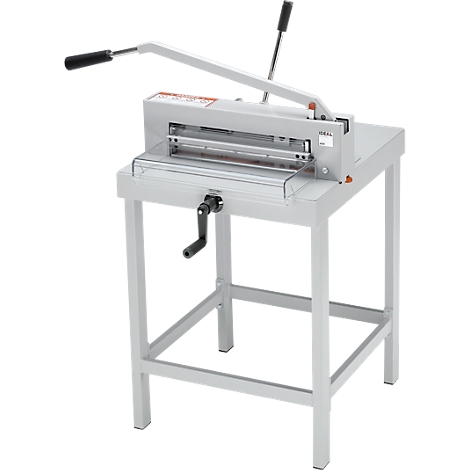 Gray paper cutter on a table. It has a long lever and a crank.