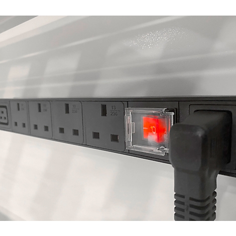 Graue Steckdosenleiste mit rotem Schalter und eingestecktem Stecker. Der Hintergrund ist weiß.
