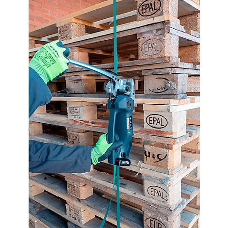 Persoon met groene handschoenen spant een band rond pallets met een blauw gereedschap. Op de achtergrond meer pallets.