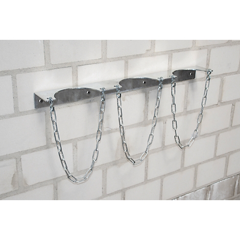 Silver gas bottle holder for three bottles, mounted on a white brick wall.