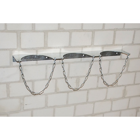 Gas bottle holder on white brick wall, three chains hanging down.