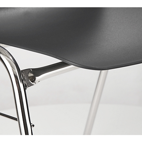 Detail shot of a chair, featuring a black seat and chrome frame. Focus on the connection of the seat and frame.