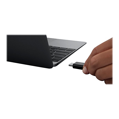 Nahaufnahme eines silbernen Laptops und einer Hand, die einen schwarzen USB-C-Adapter in den Port steckt.