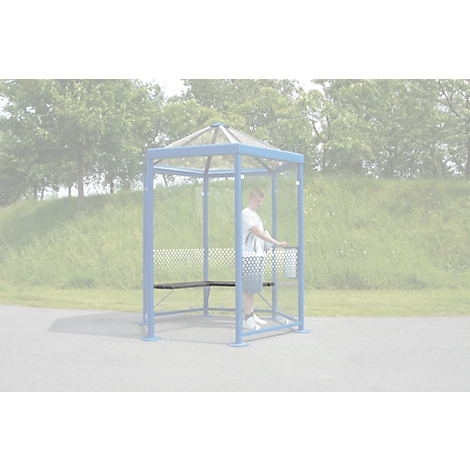 A man stands in a blue waiting shelter with a bench. Behind him is a meadow and trees.