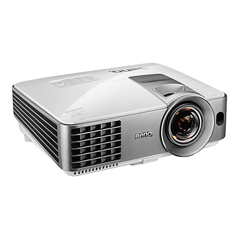 Ein weißer BenQ-Projektor, der auf einer weißen Oberfläche steht. Er hat eine graue Frontblende mit Objektiv und seitlichen Lüftungsschlitzen.