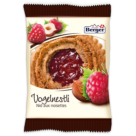Package of Vogelnestli cookies with raspberry filling, next to raspberries and hazelnut.