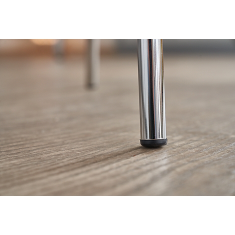 Polished metal chair leg on light wood floor. A black protective cap at the foot.