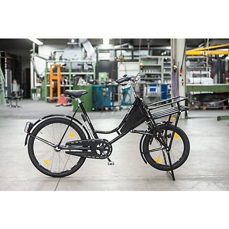 Bicicleta negra con cesta en un taller. Ruedas, cuadro y cesta son claramente visibles.