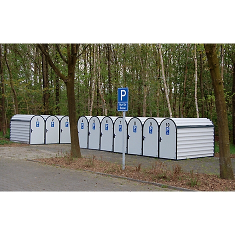 A row of white bicycle garages with blue signs. A parking sign stands in front of a forest background.