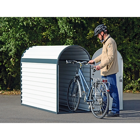 Man putting a bicycle into a white bicycle garage. He wears a helmet and a jacket.