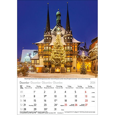 Ein weihnachtlicher Stadtblick mit beleuchtetem Weihnachtsbaum vor einem Fachwerkhaus im Abendlicht. Kalender mit Dezember-Daten.