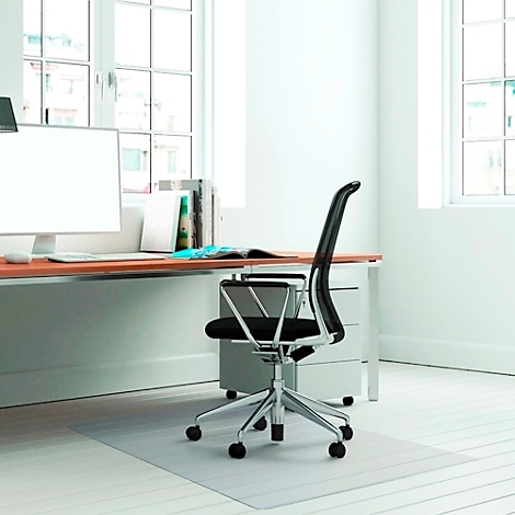 Büro mit Schreibtisch, Stuhl und Schreibtischunterlage. Fenster lassen Tageslicht herein. 