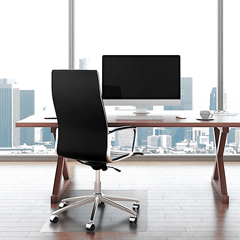 Bürostuhl vor Schreibtisch mit Monitor, Kaffeetasse und Skyline im Hintergrund.
