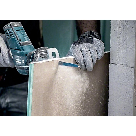 Person sägt mit einer Stichsäge eine Gipskartonplatte zu. Staub wirbelt auf, Handschuh schützt Hand.