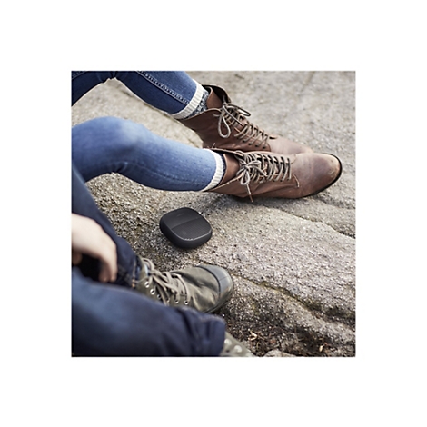 Zwei Personen sitzen auf einem Felsen. Ihre Beine sind angewinkelt und tragen Jeans und Stiefel. Dazwischen befindet sich ein schwarzer Lautsprecher.