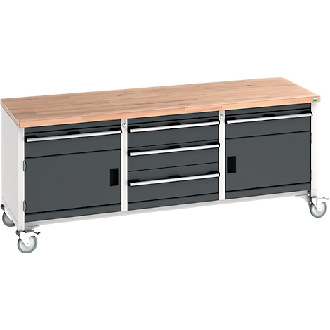 Werkbank mit Holzplatte, grauen Schränken und Rollen. Schränke mit Schubladen und Türen.