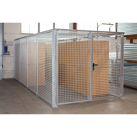 Grande cage en métal servant à entreposer des marchandises. Elle est dotée d'une porte et est placée dans un entrepôt.