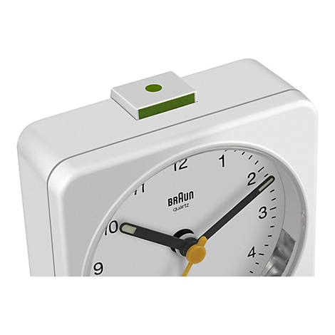 Nahaufnahme eines weißen analogen Braun-Weckers mit grünem Alarm-Knopf oben.
