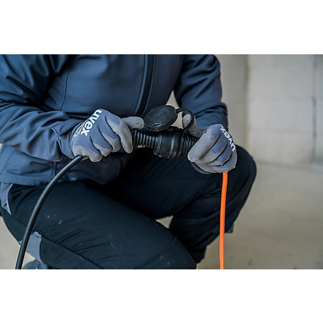 Personne agenouillée connectant un câble. Mains gantées tenant une prise et un câble orange.