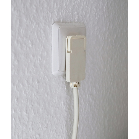 Prise de courant avec adaptateur branché et câble sur mur blanc.