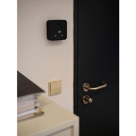 Rückseite eines schwarzen, quadratischen Geräts mit einer kreisförmigen Vertiefung und einem Haken zum Aufhängen.