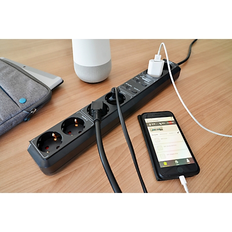 Multiprise noire avec trois prises auxquelles sont connectés divers appareils, tels qu'un smartphone et un chargeur.