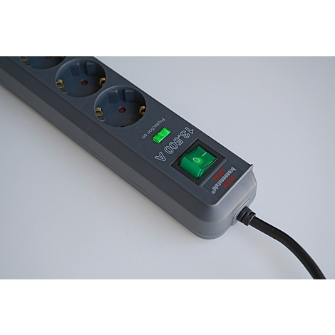 Graue Mehrfachsteckdose mit grünem Schalter und Kontrollleuchte. Schwarzes Kabel ist angeschlossen.