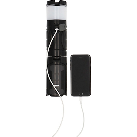 Une lampe noire charge un smartphone noir avec un câble blanc. La lampe est en plusieurs parties, avec une source de lumière blanche en haut.