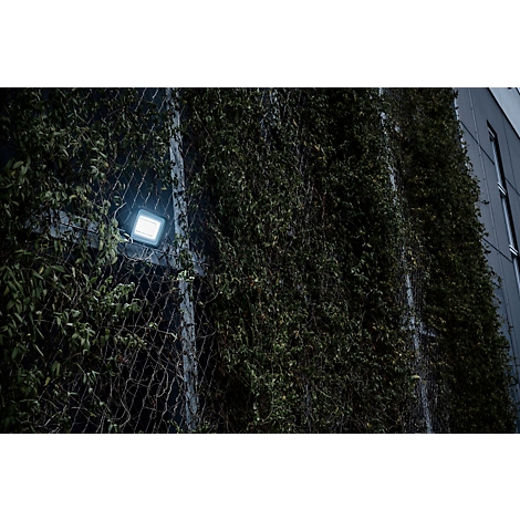 Un appareil électronique noir vu de côté, avec antenne et support.