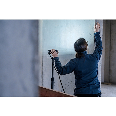 Detailopname van een zwarte microfoonstandaard. Kabels zijn bevestigd aan de poot, de rest is wazig.