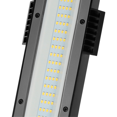 Gros plan d'une lampe LED avec des ailettes de refroidissement. Des diodes électroluminescentes jaunes brillent sur fond blanc.