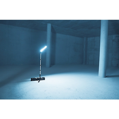 Un projecteur dans une pièce vide. Le faisceau lumineux est allumé et éclaire le sol, des piliers en béton sont visibles en arrière-plan.