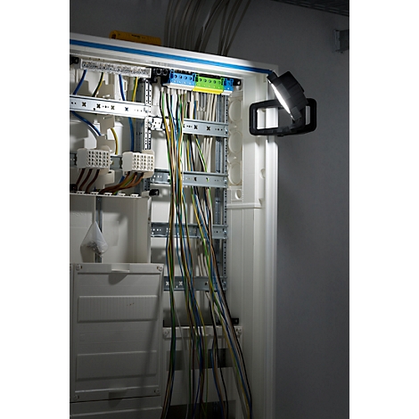 Open zekeringkast met diverse kabels, verlicht door een werklamp.