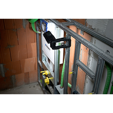 Ruwbouw met installaties voor een toilet. Metalen frame, waterleidingen, reservoir, bakstenen muur.