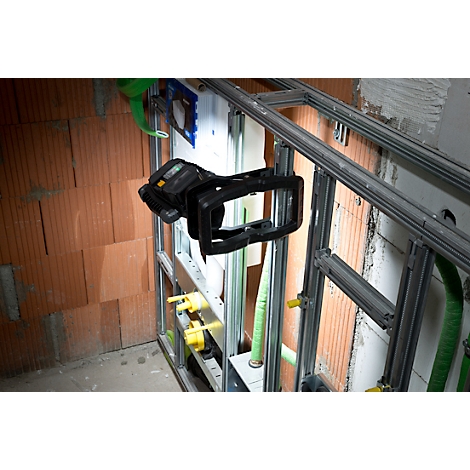 Een zwart meettoestel op een installatievoorziening voor een bakstenen muur. Gele en groene buizen zijn zichtbaar.