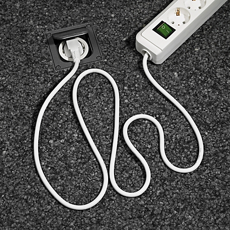 Weißes Kabel, das von einer Bodentankdose zu einer Mehrfachsteckdose führt. Der Teppich ist grau.