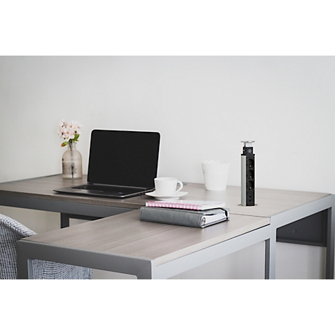 Bureau met laptop, koffiekopje, notitieboekjes, bloemenvaas en een stopcontact.