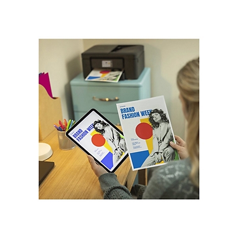 Eine Frau hält einen Ausdruck und ein Tablet mit demselben Design. Ein Drucker druckt ein ähnliches Dokument aus.