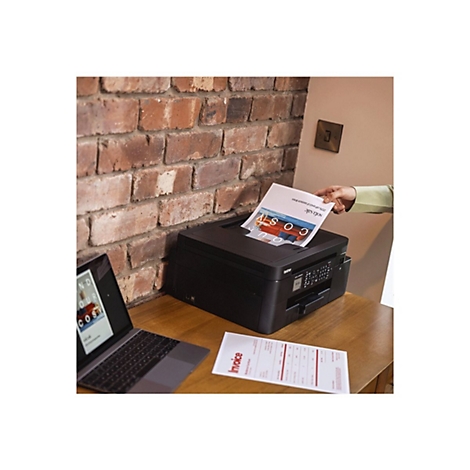 Schwarzer Drucker druckt ein Werbepapier. Auf dem Tisch liegen ein Laptop und eine Rechnung.