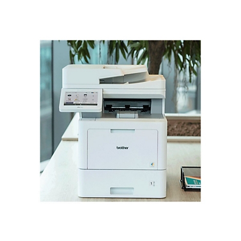 Weißer Brother-Multifunktionsdrucker auf einem Tisch. Auf dem Display werden Optionen angezeigt, der Hintergrund ist verschwommen.